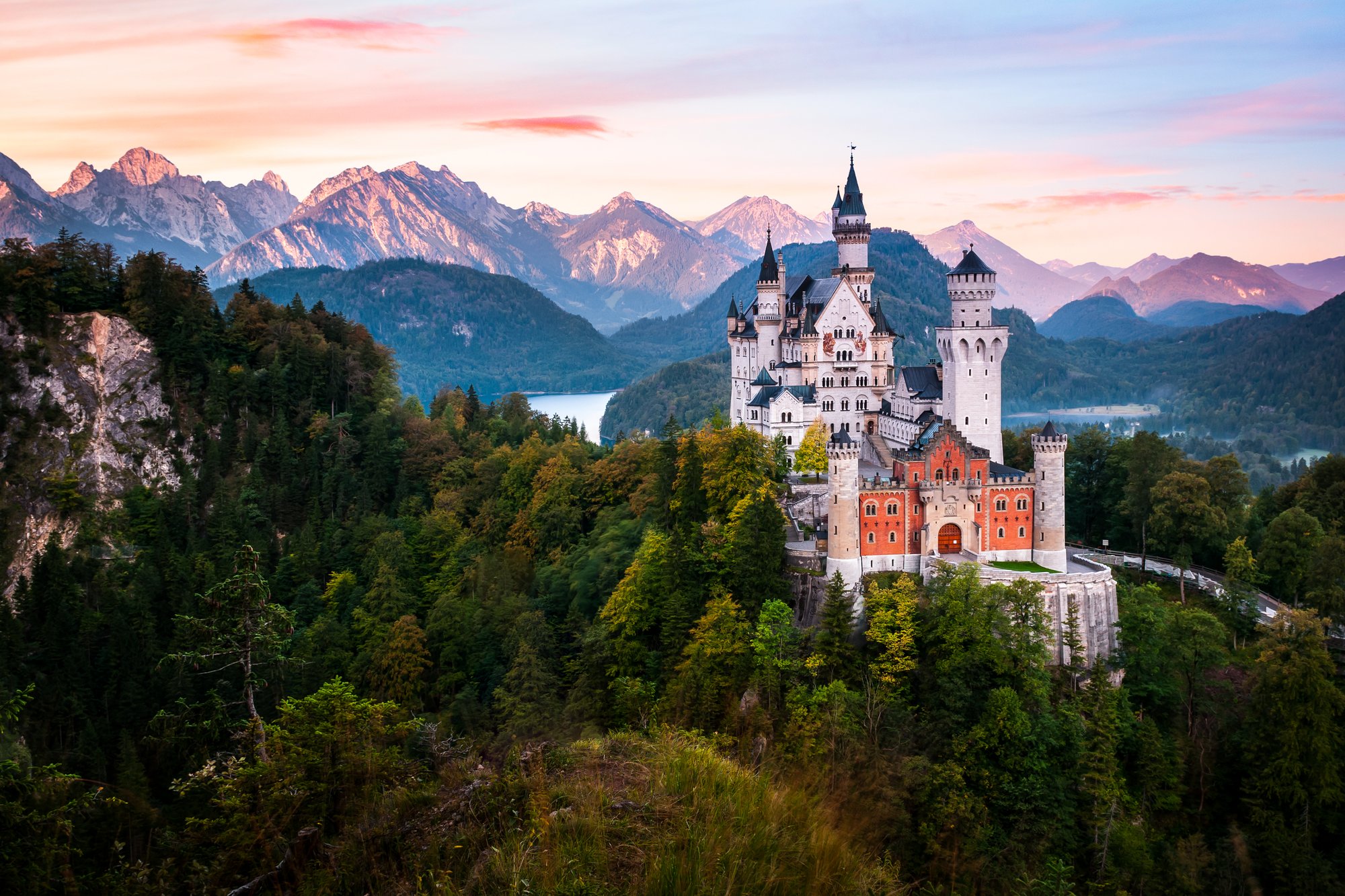 The famous Neuschwanstein castle during sunrise, with colorful panorama of Alps in the background